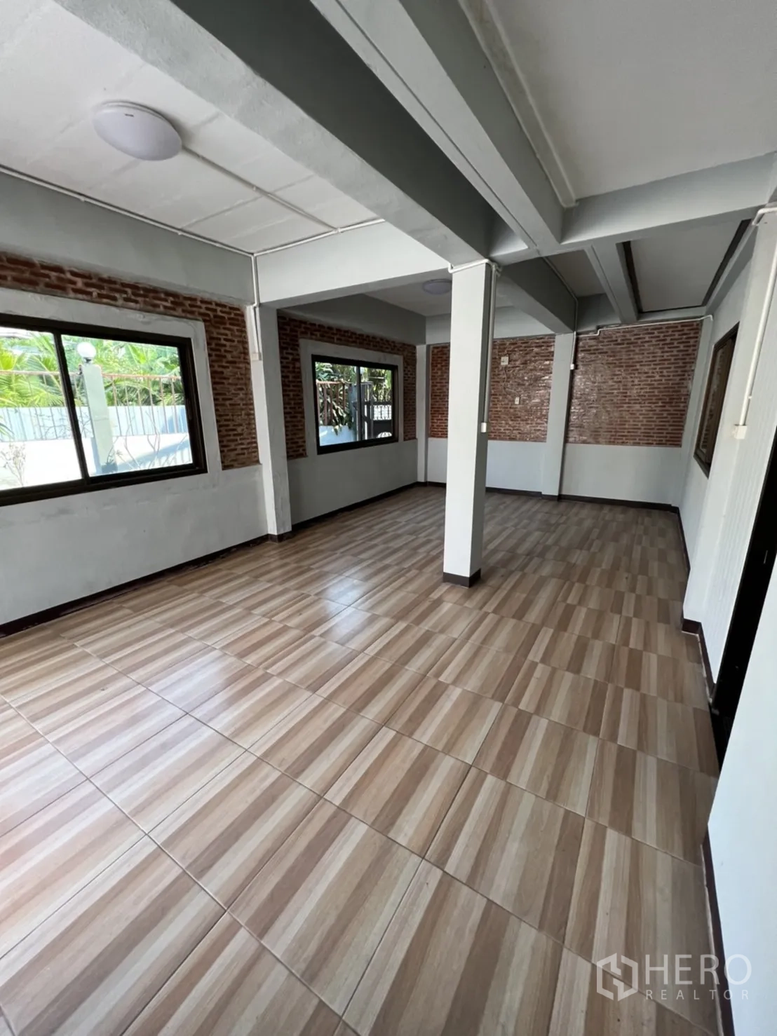 Home Office for rent in Watthana, Bangkok - Open-plan ground floor with columns, brick accent walls and large windows.