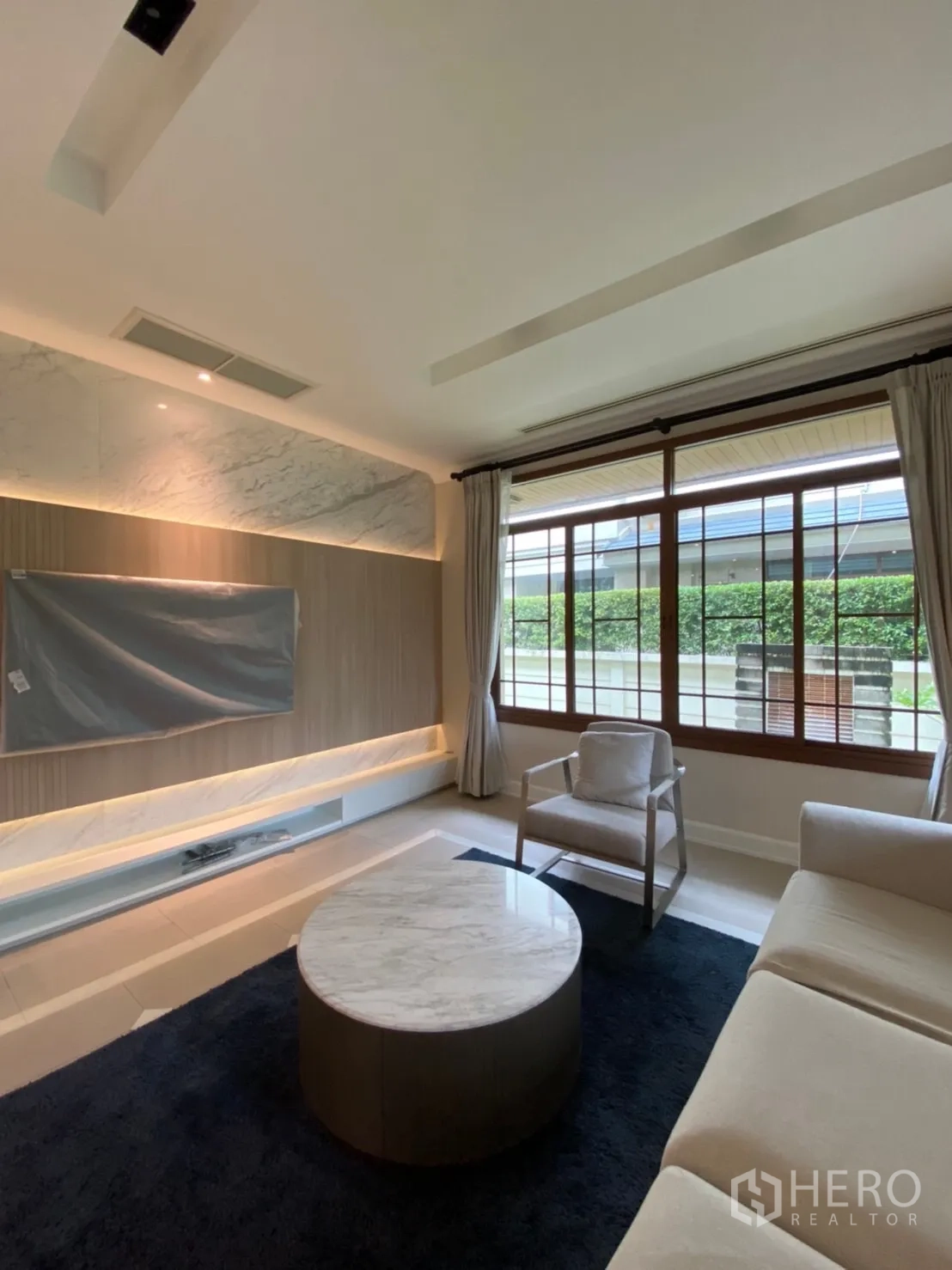 Detached House for rent in Bang Phli, Samut Prakan - Cozy living room with built-in TV wall, cove lighting, sofa and marble coffee table.