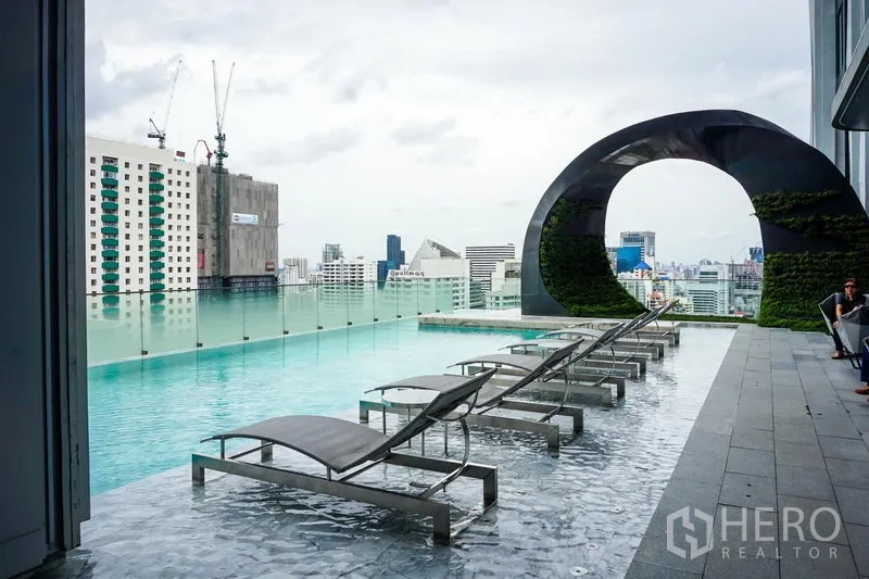 Condominium for sale in Watthana, Bangkok - Rooftop infinity pool with sun loungers and panoramic city views.