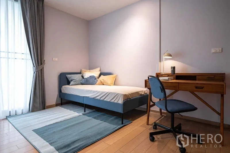 คอนโด ให้เช่าหรือขายในPathum Wan, Bangkok - ห้องนอนรองพร้อมเดย์เบด โต๊ะทำงานไม้ และผ้าม่านระเบียง