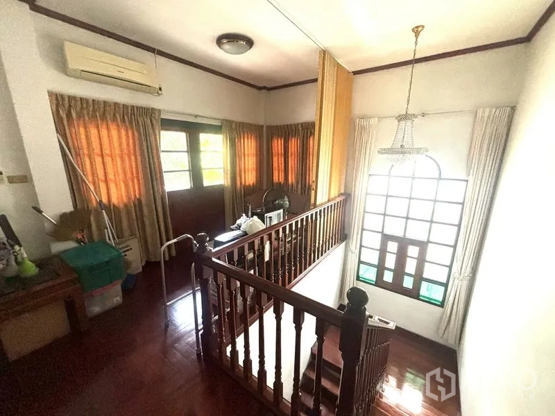 独栋房屋 for sale in Suan Luang, Bangkok - 二层楼梯平台，木楼梯、大拱窗与水晶吊灯。
