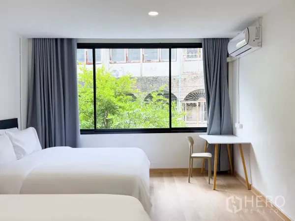 店屋 出租在Ratchathewi, Bangkok - 明亮卧室，双床、落地窗、书桌与空调。