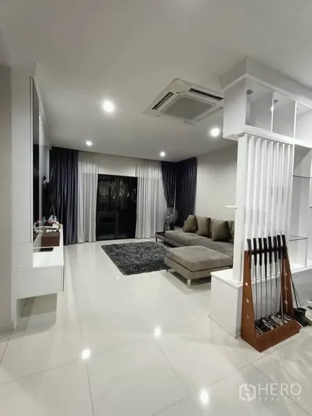 Detached House for rent - Bright living room with L-shaped sofa, white tile floors and recessed ceiling lights.