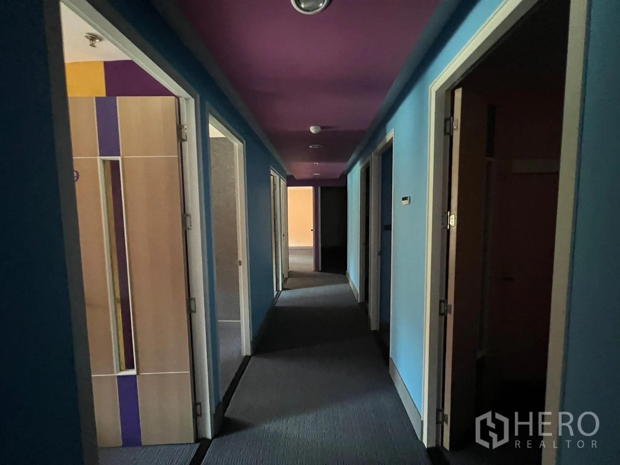 零售空间 出租 - 走廊两侧多间分房，蓝色墙面与紫色天花通向后区。