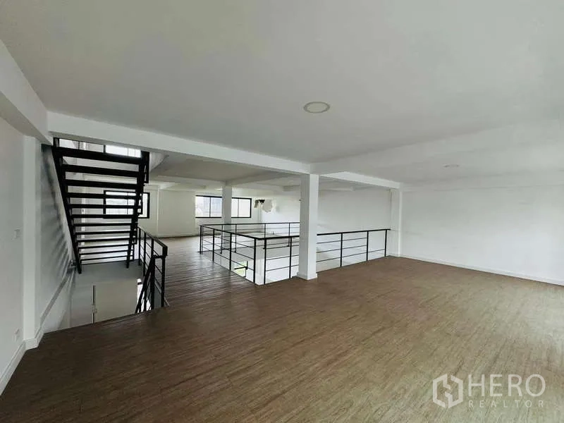 Home Office for rent in Bueng Kum, Bangkok - Loft-style upper floor with wood flooring, white walls, and a black metal staircase in a bright home office.