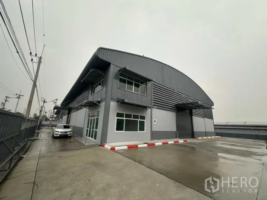 Factory for rent in Pathum Thani - Modern gray factory exterior with two-storey office and wide concrete yard in Lat Lum Kaeo.