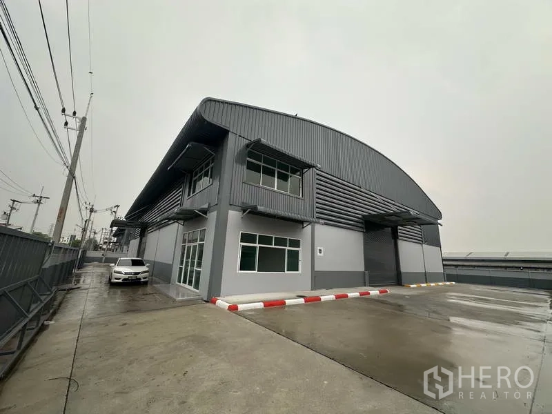Factory for rent in Pathum Thani - Modern gray factory exterior with two-storey office and wide concrete yard in Lat Lum Kaeo.