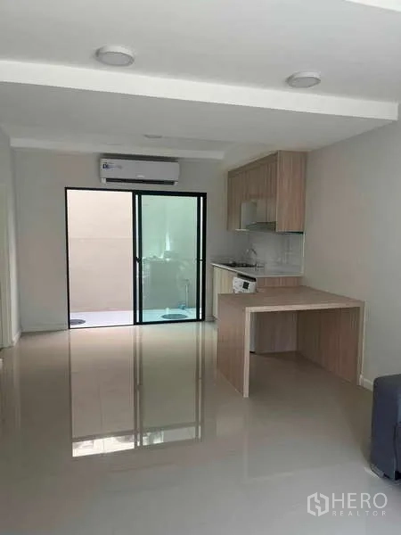 ทาวน์เฮาส์ ให้เช่าในSuan Luang, Bangkok - โถงรับแขกแบบโอเพ่นแปลน พื้นกระเบื้องเงา ประตูบานเลื่อนกระจกและครัวด้านหลัง