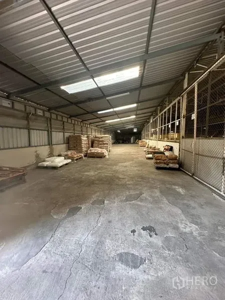 คลังสินค้า ให้เช่าในYan Nawa, Bangkok - ทางเดินโกดังยาว มีแผ่นรับแสง พื้นคอนกรีต และคอกเก็บของตาข่าย