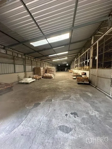คลังสินค้า ให้เช่าในYan Nawa, Bangkok - ทางเดินโกดังยาว มีแผ่นรับแสง พื้นคอนกรีต และคอกเก็บของตาข่าย