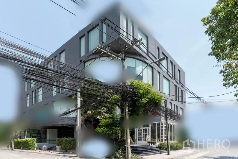 零售空间 出租在Watthana, Bangkok - 曼谷瓦他那区现代多层商业楼外观，大窗与绿化角落。