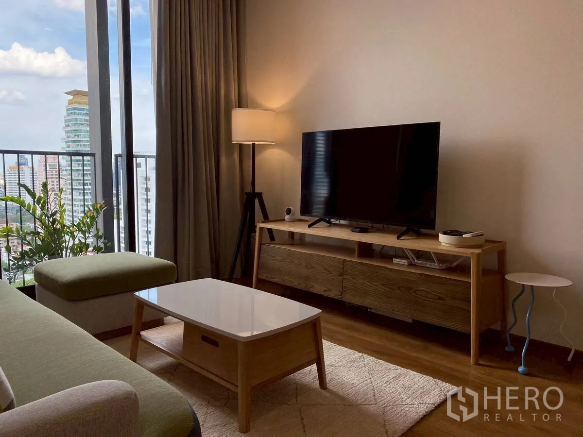 Condominium for rent in Watthana, Bangkok - Living room with TV console, coffee table, and balcony window facing the skyline.