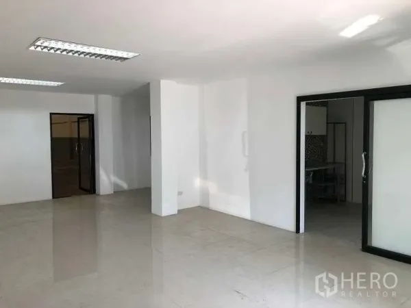 Factory for rent or sale in Bang Phli, Samut Prakan - Open-plan office area with sliding glass partitions, glossy tiles and ceiling fluorescent lighting.