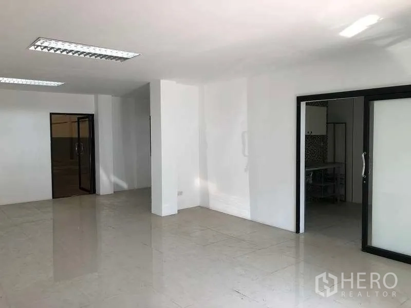 Factory for rent or sale in Bang Phli, Samut Prakan - Open-plan office area with sliding glass partitions, glossy tiles and ceiling fluorescent lighting.