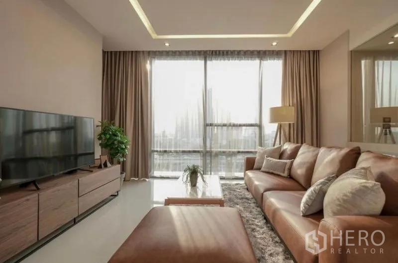 คอนโด ให้เช่าในSathon, Bangkok - ห้องนั่งเล่นรับแสงธรรมชาติ ผนังกระจกเต็มบาน โซฟาหนังและชั้นวางทีวีพร้อมวิวเมือง