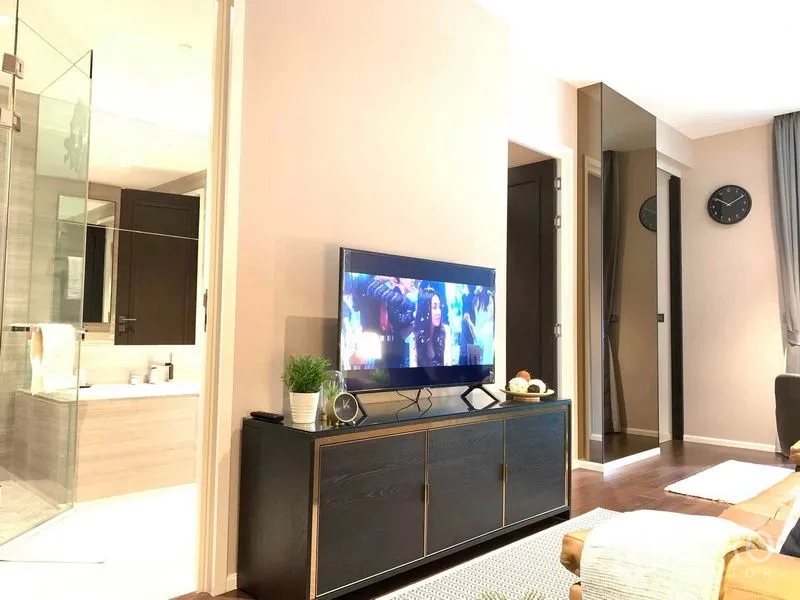 Condominium for rent in Watthana, Bangkok - Living room with TV console facing a bathroom suite behind a glass partition.