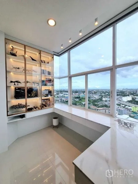 คอนโด ขาย - มุมทำงานริมกระจกโค้งรอบ พร้อมตู้โชว์ไฟในตัว และวิวสกายไลน์กรุงเทพฯ พาโนรามา