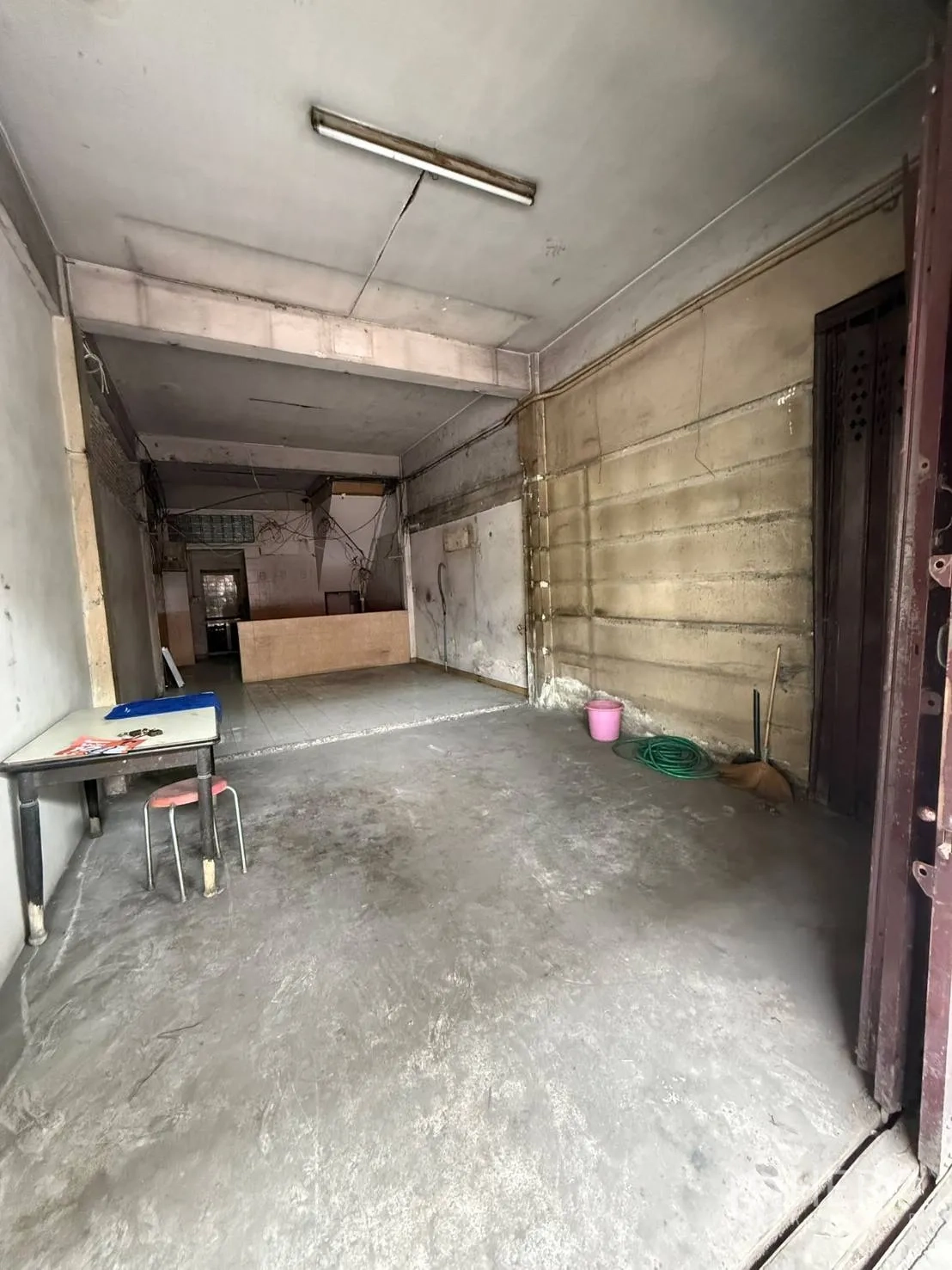 店屋 for rent in Khlong Toei, Bangkok - 从门面望向深进的底层走廊，墙边有小桌与清洁工具。
