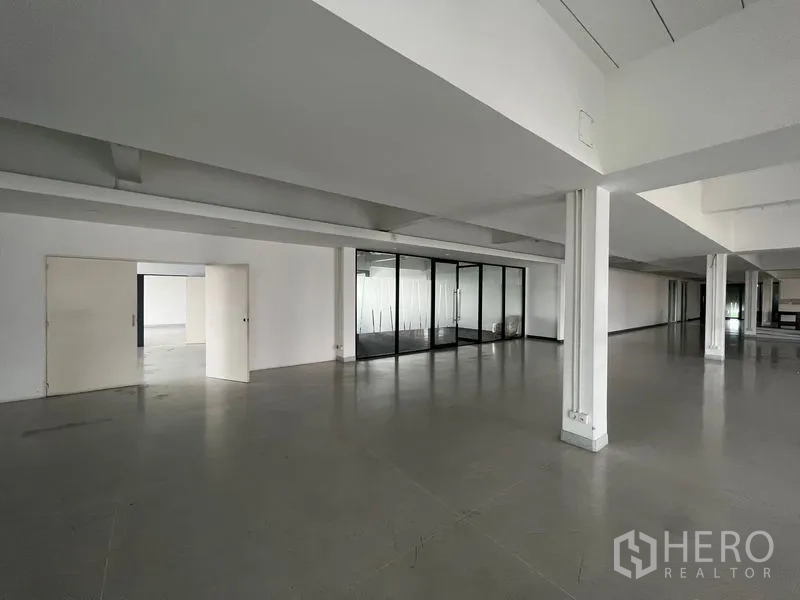 Office Space for rent in Mueang Samut Prakan, Samut Prakan - Long open office floor with pillars, polished concrete and glass partitions.