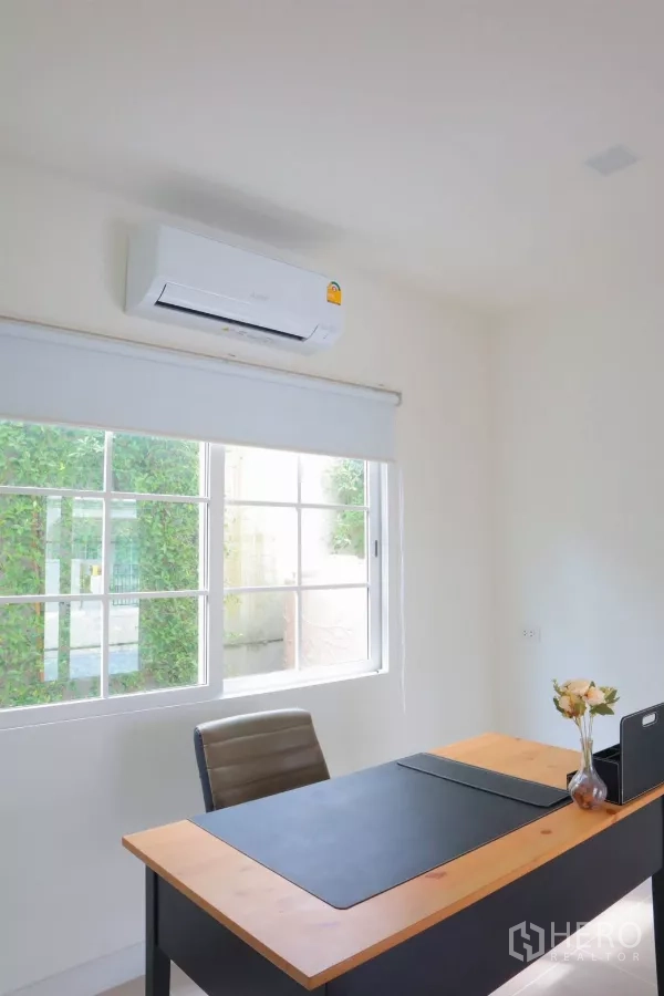 Detached House for rent in Bang Phli, Samut Prakan - Multipurpose ground-floor room staged as a home office with large window and air conditioner.