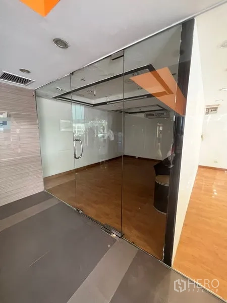 零售空间 出租 - 购物中心走廊内的零售铺位，落地玻璃门面、木地板与筒灯照明。