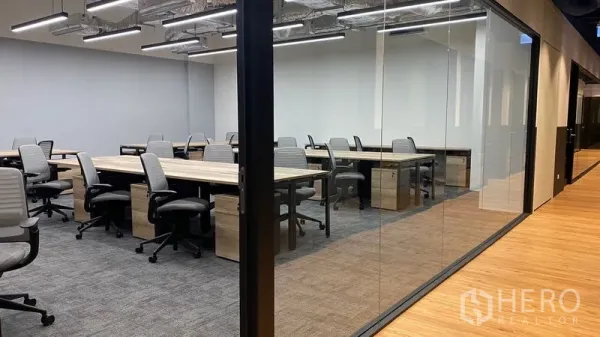 办公空间 出租在Pathum Wan, Bangkok - 玻璃隔断的办公区，配共享工位、地毯地面、裸顶管线与木质走廊