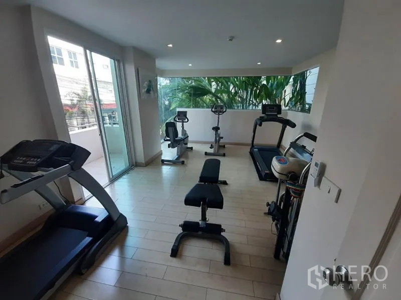 Condominium for sale in Wang Thonglang, Bangkok - Condominium fitness room with treadmills, bikes and weight bench overlooking greenery.