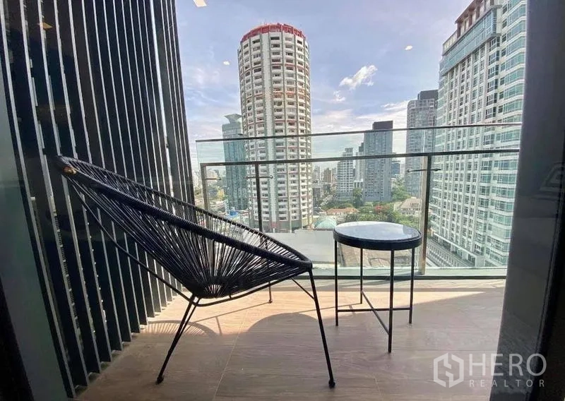 Condominium for rent in Watthana, Bangkok - Private balcony with lounge chair and side table overlooking the Bangkok skyline.