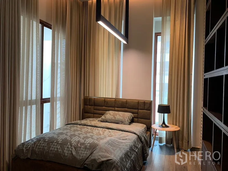 Condominium for rent - Bedroom with large windows, upholstered headboard and pendant light.