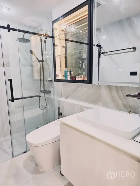 Condominium for sale in Bang Rak, Bangkok - Contemporary bathroom with glass shower enclosure, rain shower and white vanity.