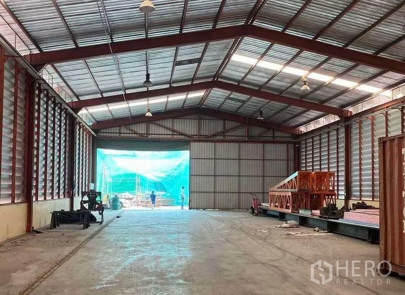 Factory for rent in Bang Kruai, Nonthaburi - End bay of factory with large shutter opening, high roof, clear concrete floor and staging area for loading.