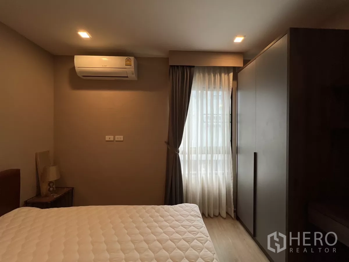 ทาวน์เฮาส์ ให้เช่าในSuan Luang, Bangkok - อีกมุมของห้องนอนที่มองเห็นตู้เสื้อผ้า โต๊ะข้างเตียง และไฟสลัว