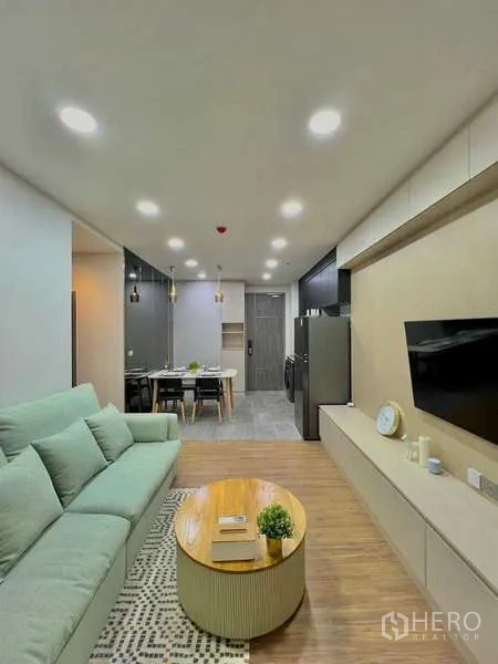 Condominium for sale in Watthana, Bangkok - View of living area toward entrance, built-in TV console and round coffee table.