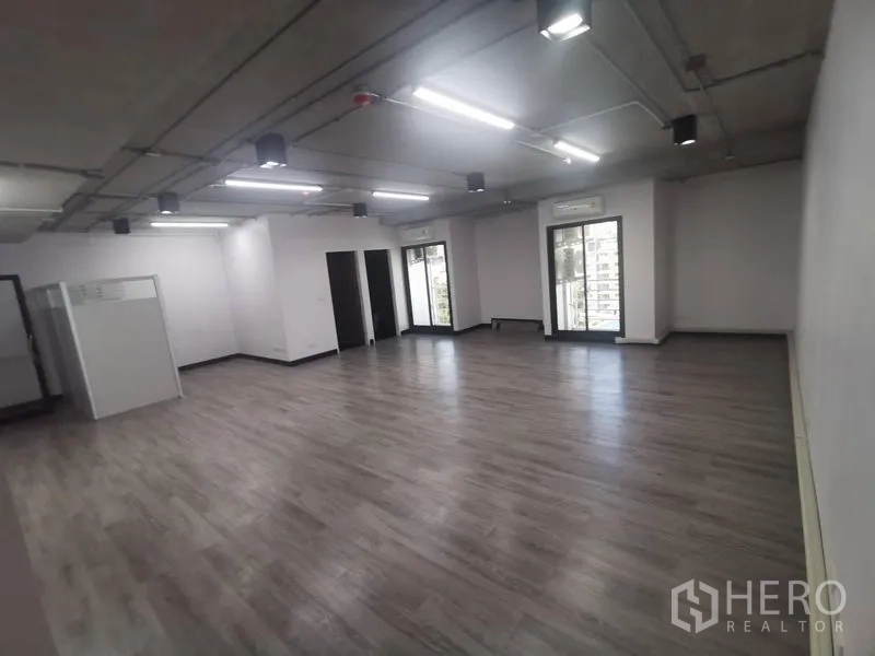 Office Space for rent - Wide-angle view of bright open workspace with glass doors opening to an outdoor outlook and ample floor area.