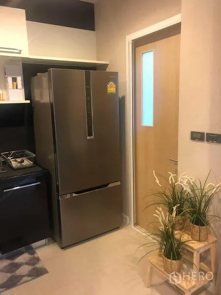 บ้าน ให้เช่าหรือขายในBang Kapi, Bangkok - ครัวกะทัดรัดมีตู้เย็นสแตนเลสและประตู ตกแต่งด้วยต้นไม้