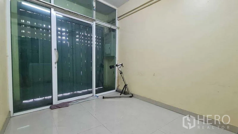 Shophouse for sale in Watthana, Bangkok - Ground-floor room with sliding glass storefront and glossy tiled floor.
