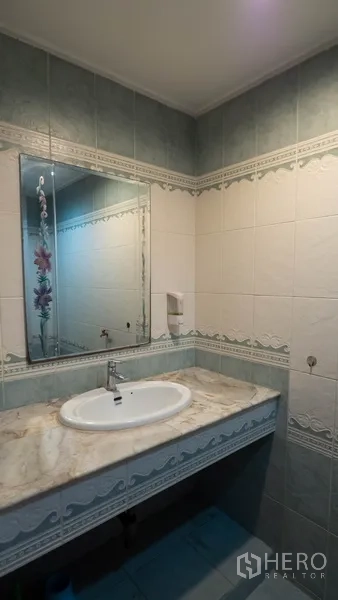 Townhouse for rent in Khlong Toei, Bangkok - Bathroom with marble vanity, large mirror and green‑and‑white tiles.