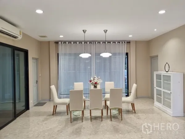 Detached House for rent in Bang Khae, Bangkok - Bright dining room featuring a glass table, six upholstered chairs, pendant lights, and sheer curtains.