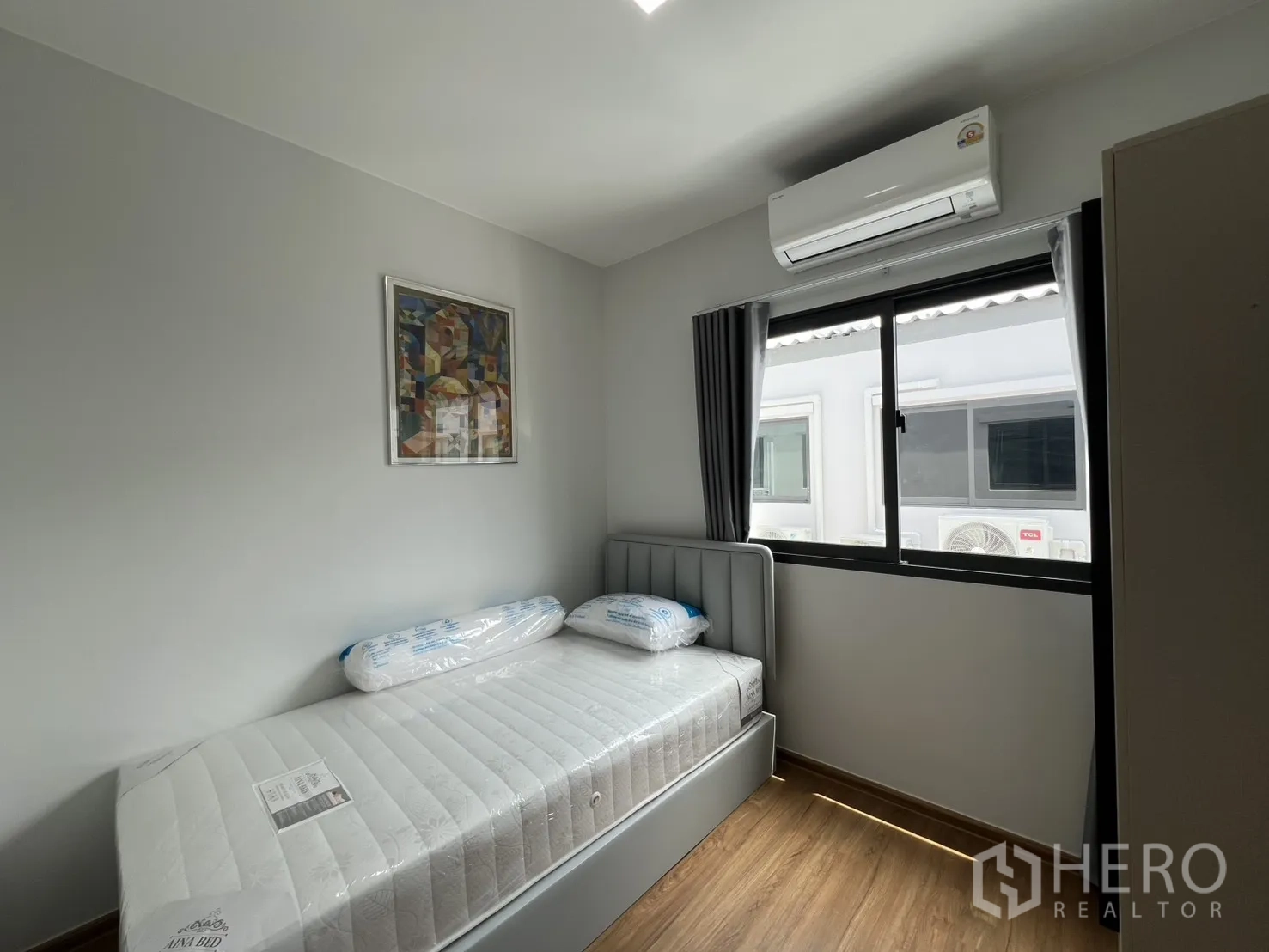 Townhouse for rent in Bang Phli, Samut Prakan - Compact single bedroom with grey bedframe, window and blackout curtains.