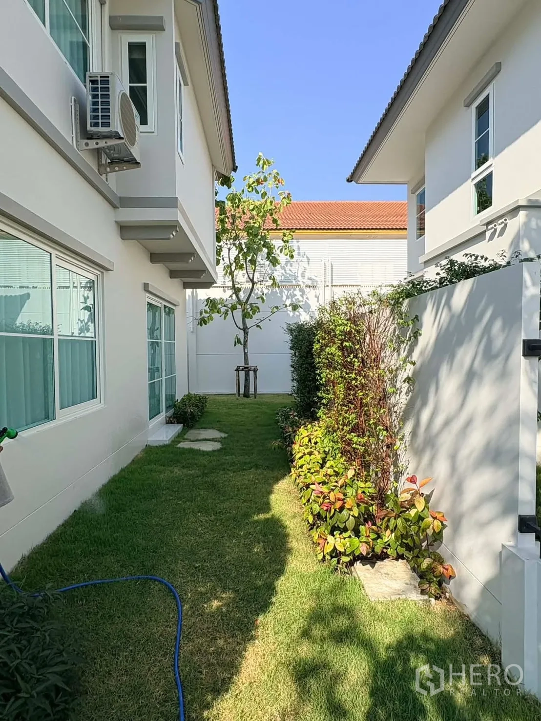 独立式住宅 for rent in Bang Phli, Samut Prakan - 两栋房屋之间的侧院草坪，花坛与小树成荫。
