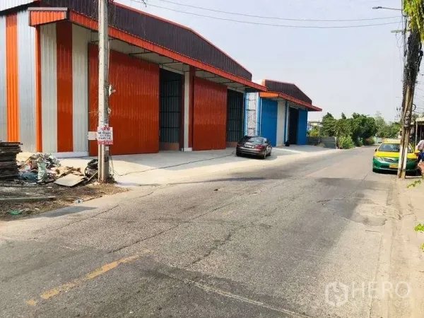 货栈 出租在Bueng Kum, Bangkok - 街景视角的彩色金属外墙仓库，带宽阔装卸区与停放车辆，位于Bueng Kum。