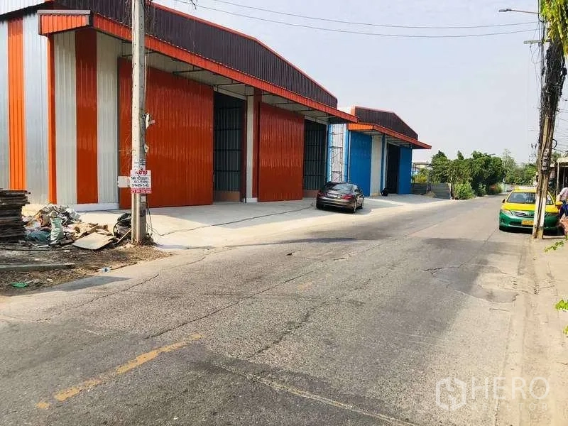 货栈 出租在Bueng Kum, Bangkok - 街景视角的彩色金属外墙仓库，带宽阔装卸区与停放车辆，位于Bueng Kum。