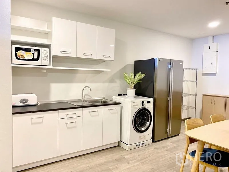 คอนโด ให้เช่า - ภาพใกล้ครัวกะทัดรัด อ่างล้างจาน ไมโครเวฟ เครื่องซักผ้า และตู้เย็นสแตนเลส