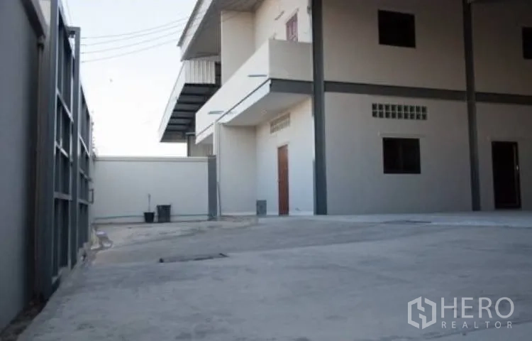 Warehouse for rent in Bang Phli, Samut Prakan - Paved compound area next to a two-storey office building within the site.