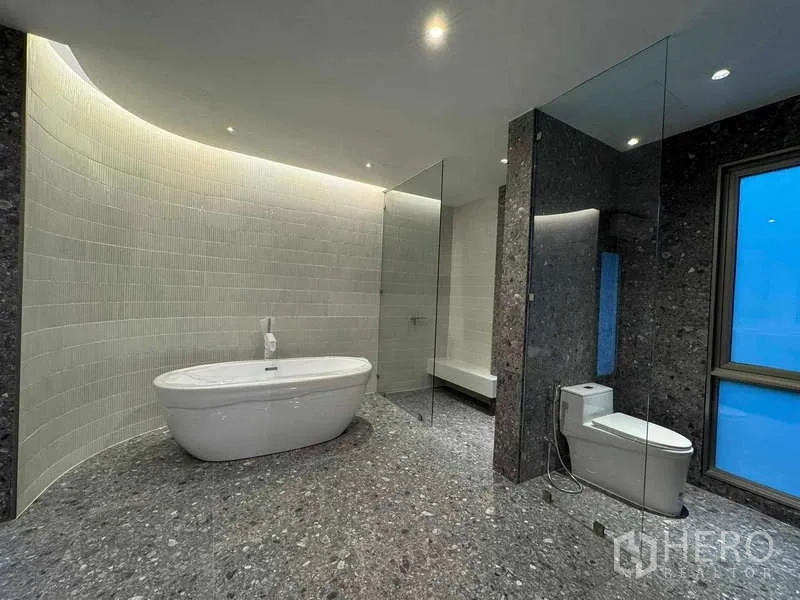 Home Office for sale in Chatuchak, Bangkok - Luxury bathroom with freestanding bathtub, glass shower, gray stone flooring and cove lighting.