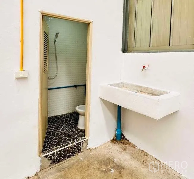 Warehouse for rent in Pak Kret, Nonthaburi - Utility corner in the warehouse with concrete sink and doorway to shower and toilet.
