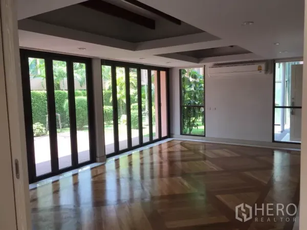 Detached House for rent in Sathon, Bangkok - Living room with floor-to-ceiling folding glass doors, coffered ceiling and garden view