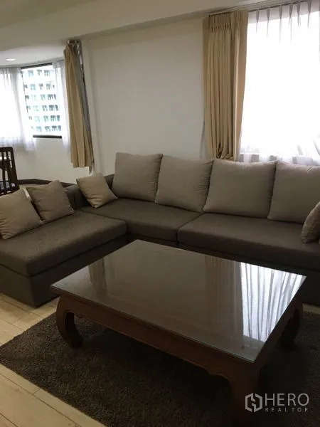 คอนโด ให้เช่าในWatthana, Bangkok - โซฟาเข้ามุมพร้อมหมอน และโต๊ะกลางไม้ ข้างหน้าต่างผ้าม่านแสงสว่าง
