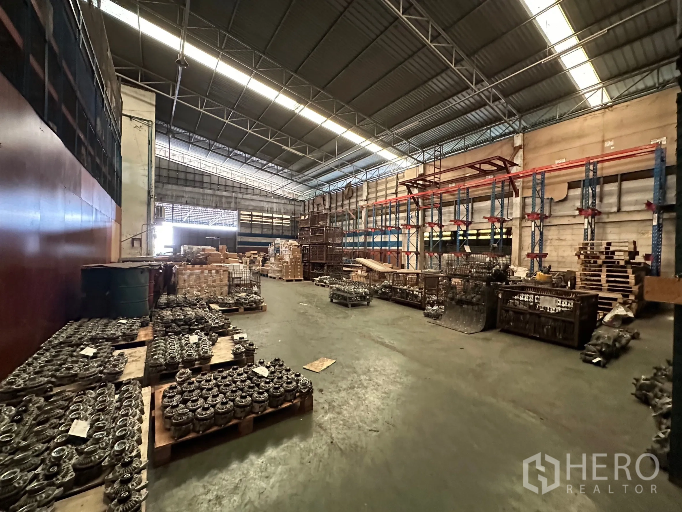 工厂 出租在Lam Luk Ka, Pathum Thani - 高挑钢结构屋顶的宽敞厂房通道，两侧为托盘与货架。