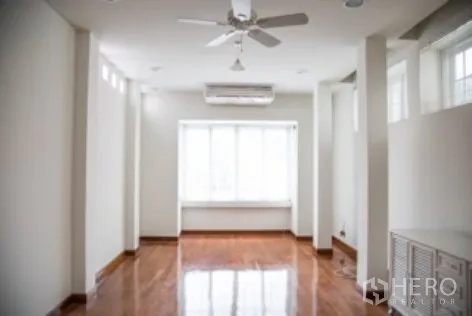 บ้าน ให้เช่าในKhlong Toei, Bangkok - ห้องนั่งเล่นทรงยาว พื้นไม้ พัดลมเพดาน และม้านั่งริมหน้าต่าง